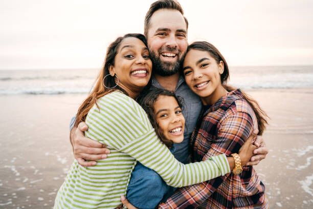 Smiling parents with two children on the beach fam Family Counseling
